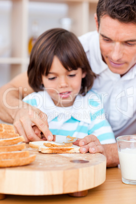 Affectionate father and his son spreading jam on bread