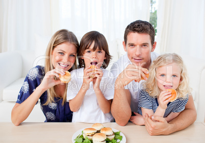 Enthusiastic family eating burgers in the living room