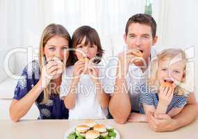 Hungry family eating burgers in the living room