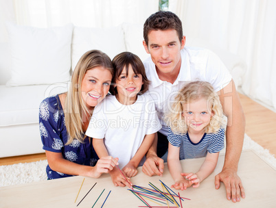 Cheerful family playing mikado in the living room