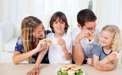 Loving family eating burgers in the living room