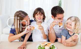 Loving family eating burgers in the living room