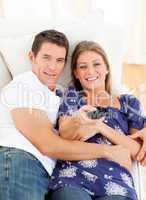 Relaxed lovers watching television lying on sofa
