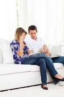 Distressed couple doing their accounts sitting on sofa