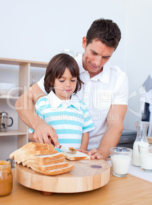 Charming father and his son spreading jam on bread