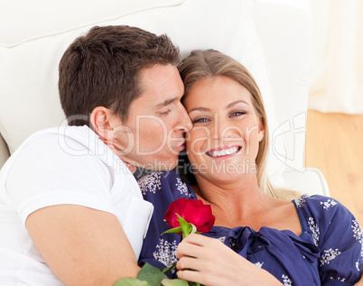 Portrait of a charming man kissing his wife lying on sofa