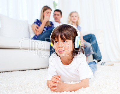Smiling little boy listening music lying on floor