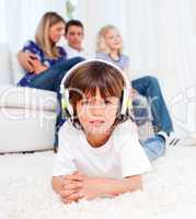 Cute little boy listening music lying on floor