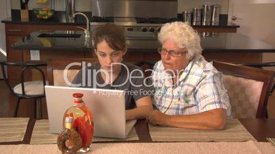 Teen girl teaches elderly woman on computer