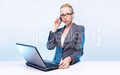 blonde businesswoman using laptop computer and mobile phone  at