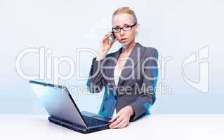 blonde businesswoman using laptop computer and mobile phone  at