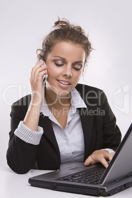 woman using a laptop computer and talking on the phone