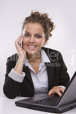 woman using a laptop computer and talking on the phone