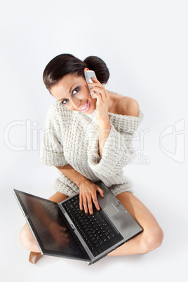 Brunette talking at a cellphone and working at laptop