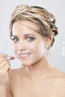 Portrait of beautiful young woman applying lipstick.
