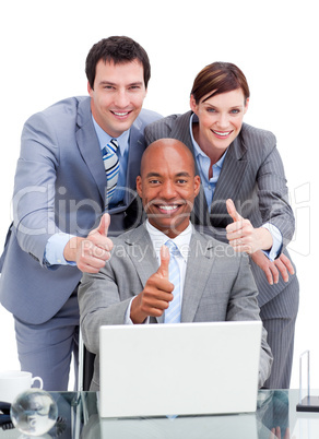 Diverse business co-workers with thums up at a laptop