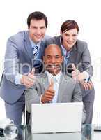 Diverse business co-workers with thums up at a laptop