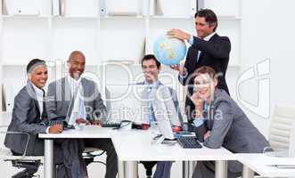 Smiling manager holding a globe with his team working at compute