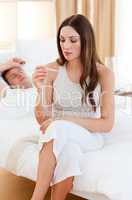 Caring woman taking her sick husband's temperature