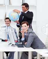 Happy manager holding a globe with his team working at computers