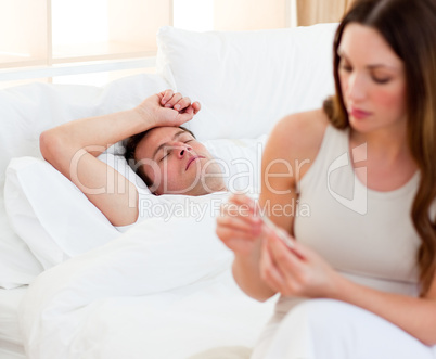 Concerned woman taking her sick husband's temperature