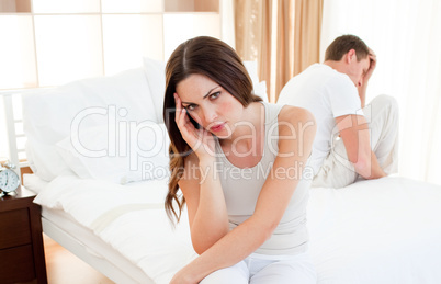 Upset couple sitting separately on their bed