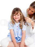 Pretty woman brushing her daugther's hair