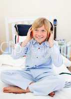 Smiling boy listening music sitting on bed