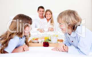 Cheerful family having breakfast sitting on bed