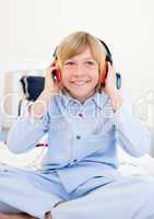 Laughing boy listening music sitting on bed