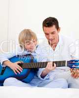 Smiling little boy playing guitar with his father