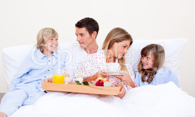 Loving family having breakfast sitting on bed