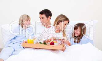 Loving family having breakfast sitting on bed