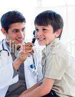 Handsome doctor examining little boy's ears