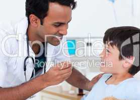 Handsome doctor giving medicine to a little boy