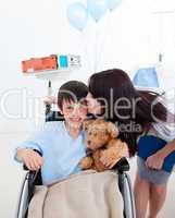 Cheerful little boy sitting on wheelchair and his mother