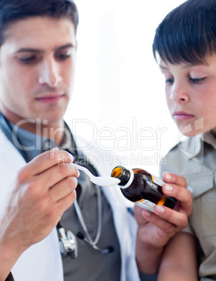 Concentrated doctor giving medicine to a little boy