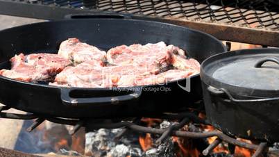 Mutton steaks cooking in cast iron outside