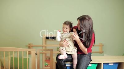 Female teacher with little girl in kindergarten
