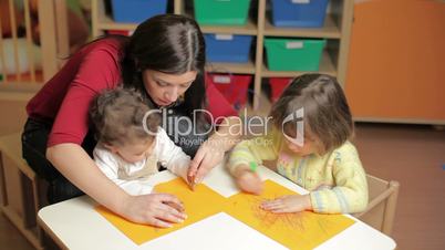 little girls and teacher playing with colors