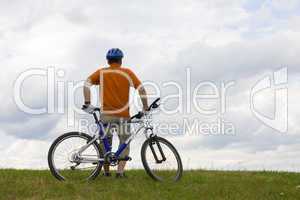 Mann steht mit Mountainbike auf Wiese