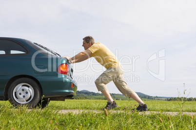 Mann schiebt ein Auto