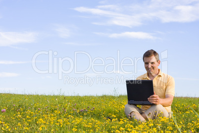 Man mit Laptop auf Wiese