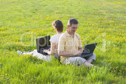 Paar mit Laptops auf Wiese