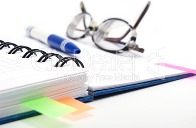 pen and glasses on notebook with bookmarks