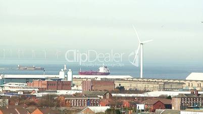 Wind turbines on land with many more in the distance out at sea