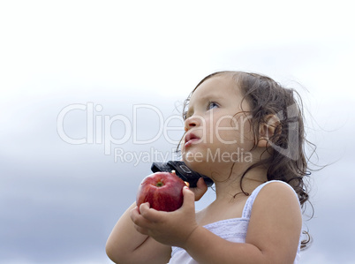 Baby girl holding an apple whilst talking on a cellphone