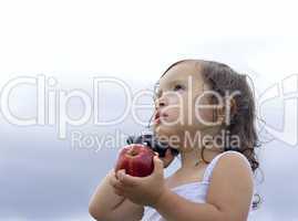 Baby girl holding an apple whilst talking on a cellphone