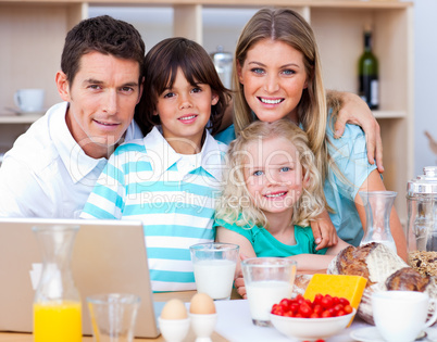 Joyful family using laptop during the breakfast