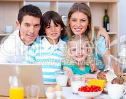 Joyful family using laptop during the breakfast